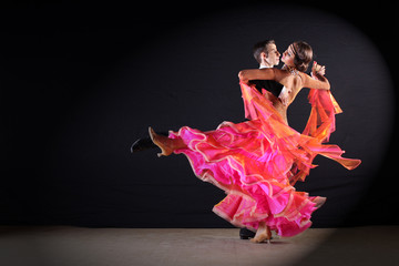 Latino dancers in ballroom against black background