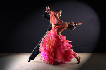 Latino dancers in ballroom against black background