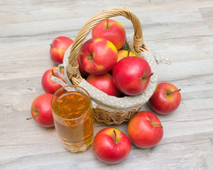 basket of apples and a glass of juice on a wooden table