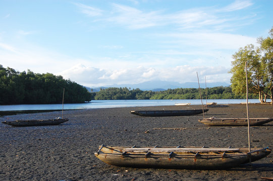 Timber canoe at sand near river