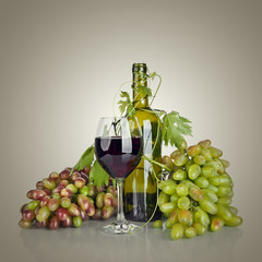 bottle, glass of wine and ripe grapes