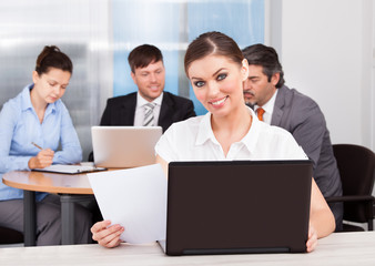 Obraz premium Businesswoman Using Laptop In Front Of Her Colleagues