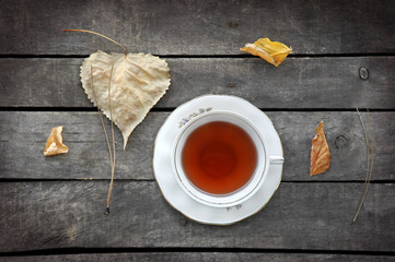 autumn tea in white vintage cup on old wooden table