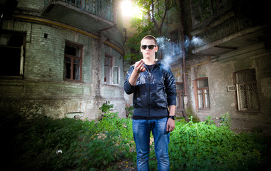 portrait of young man in sunglasses holding reeky cigarette