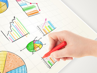 Business person drawing colorful graphs and icons on paper