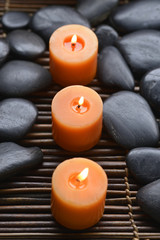 Obraz na płótnie Canvas Row of candle and spa stones on mat