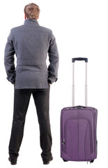Back view of young man traveling with suitcas.