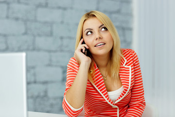 Fototapeta premium Young businesswoman talking on phone and looking up at copyspace