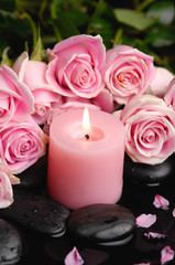 Fototapeta na wymiar Branch roses and black stones, candle with green leaf
