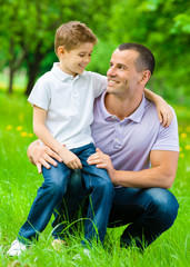 Father keeps son on the knee in the green park