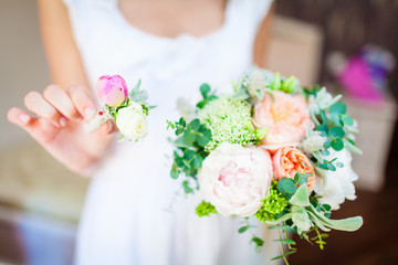 bride holding a wedding bouquet and a buttonhole