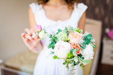 bride holding a wedding bouquet and a buttonhole