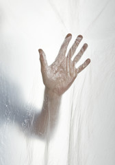 Silhouette of a hand behind a transparent plastic