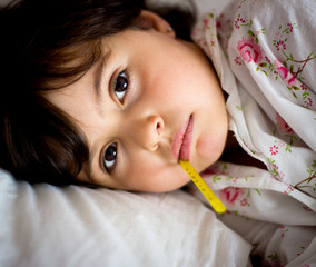 little girl with thermometer in bed