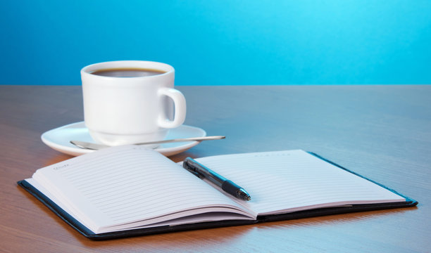 Open notepad, cup of coffee and saucer