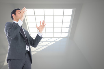 Composite image of unsmiling businessman with arms raised