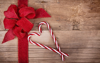 Candy canes and ribbon on wooden background