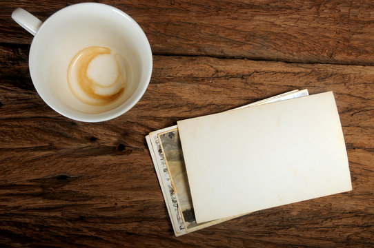 Empty coffee cup and old paper photo frame on wood background