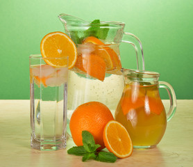 Jugs with drinks, glass and oranges