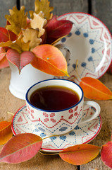 A cup of tea on the table with autumn leaves