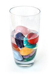 Crystals in half filled glass of water, on white