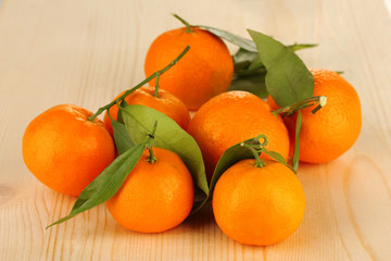 Sweet tangerines with leaves, on wooden background