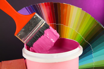 Paint pot, paintbrush and coloured swatches close up