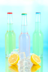 Drinks in glass bottles with ice cubes on blue background