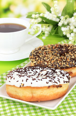 Sweet donuts with cup of tea on table on bright background