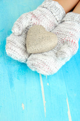 Female hands in mittens with heart on wooden background