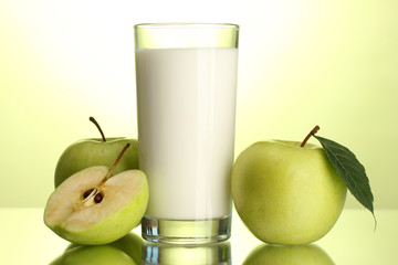 Glass of kefir and apples, on green background