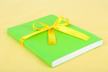 Book wrapped with color ribbon, on color background
