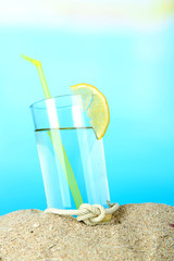 Beach cocktail in sand on blue background