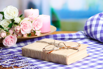 Composition with old book, eye glasses, candles, flowers and
