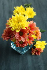 Chrysanthemum flowers in vase on wooden table close-up