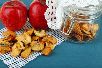 Dried apples in glass jar, on color wooden background