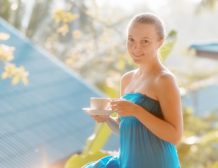 Young woman drinking coffee on morning terrace