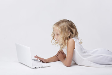 Beautiful blonde little girl with netbook, white background