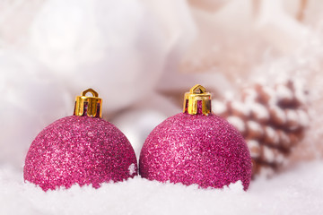 pink christmas bauble decoration with fir cone in snow