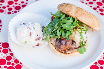 hamburger with arugula, bacon and potato salad on the side