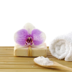 Obraz na płótnie Canvas orchid on soap with salt in spoon with towel on mat