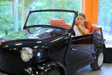A pretty woman driving a retro black car