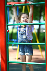 Obraz premium Happy girl hanging on gymnastic wall on playground