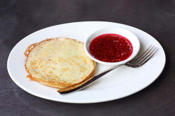 Pancakes with raspberry jam on a plate with a fork