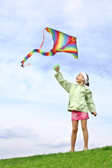 Girl launches colorful kite on a blue sky with clouds