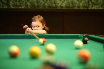 Cute little girl with pigtails playing pool