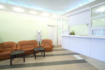 Empty light reception area with two chairs, sofa and tables