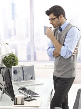 Businessman drinking coffee standing in office