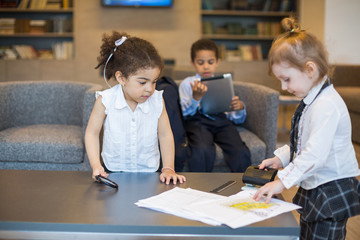 children with stationery, girl makes hole in paper.