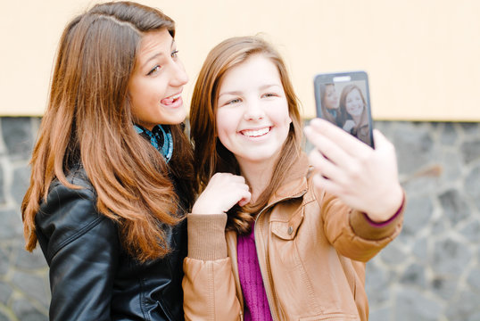 Two teen girls taking picture of themselves using tablet pc